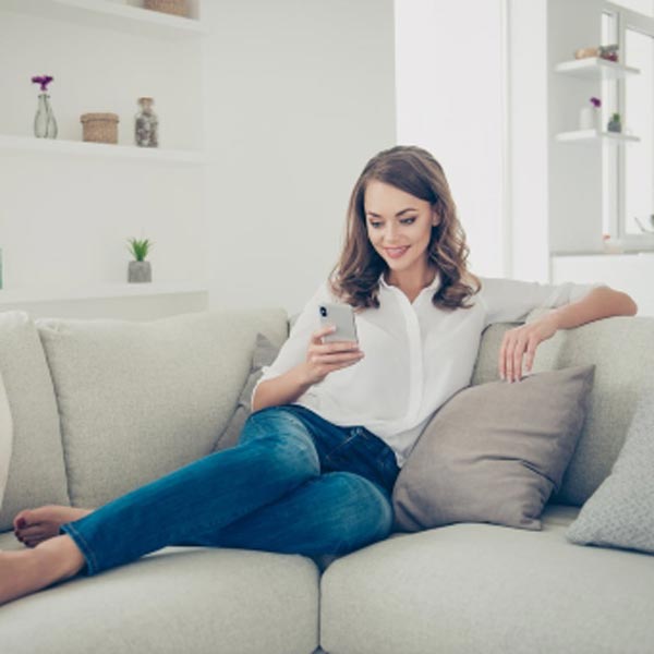 woman sitting on couch using phone